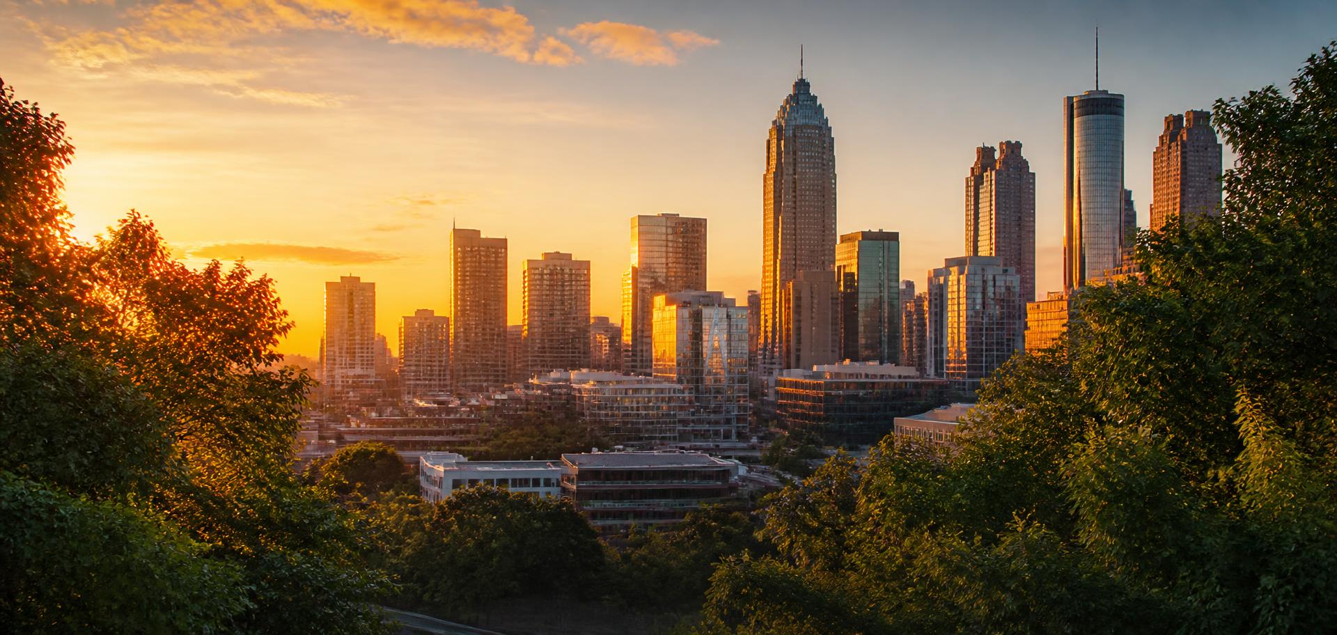 Atlanta, Georgia skyline at sunset framed by green trees